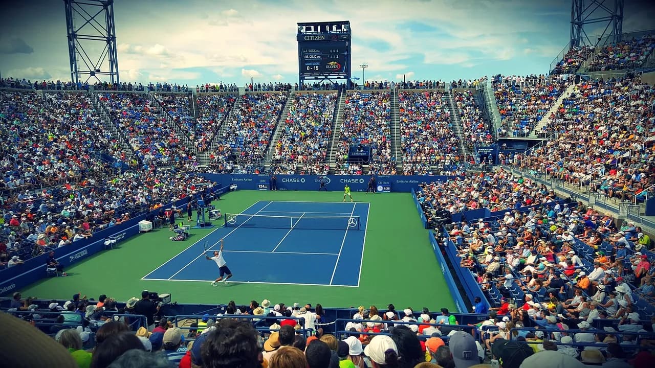 A tennis match on a hard court in a full stadium