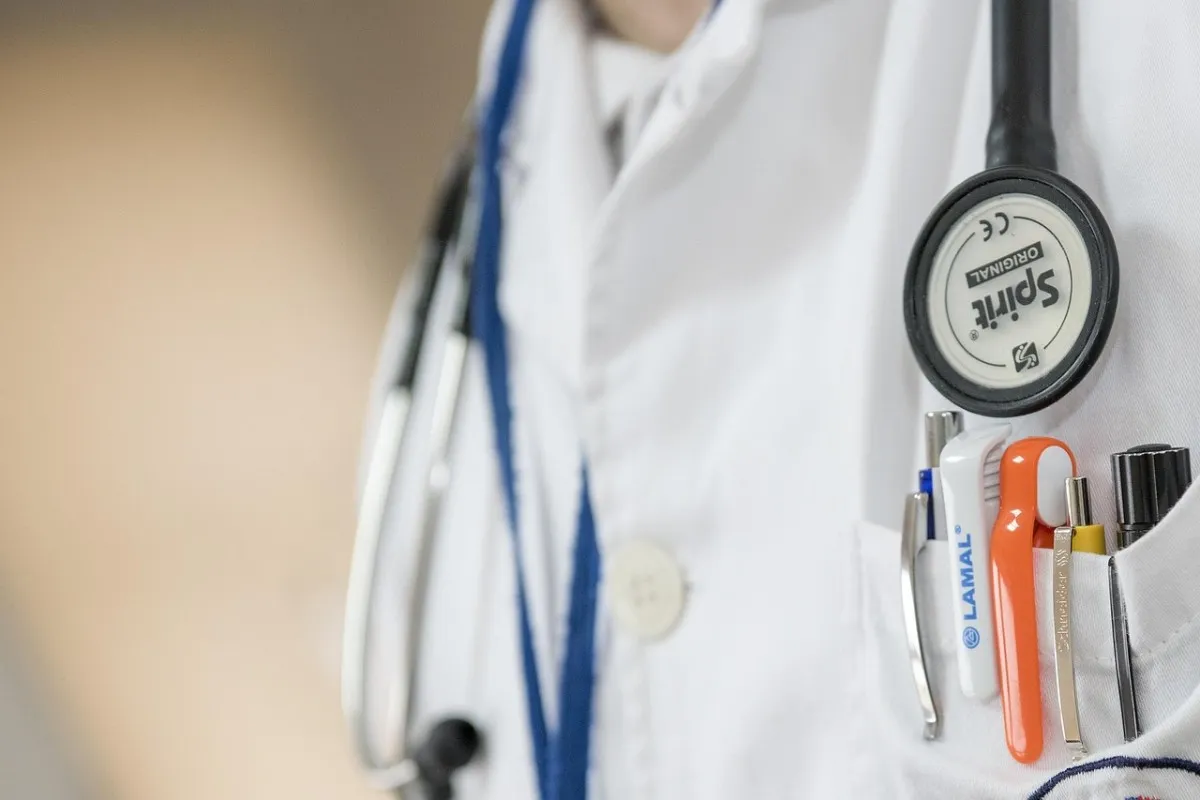 A stethoscope and pens in a doctor's white coat pocket