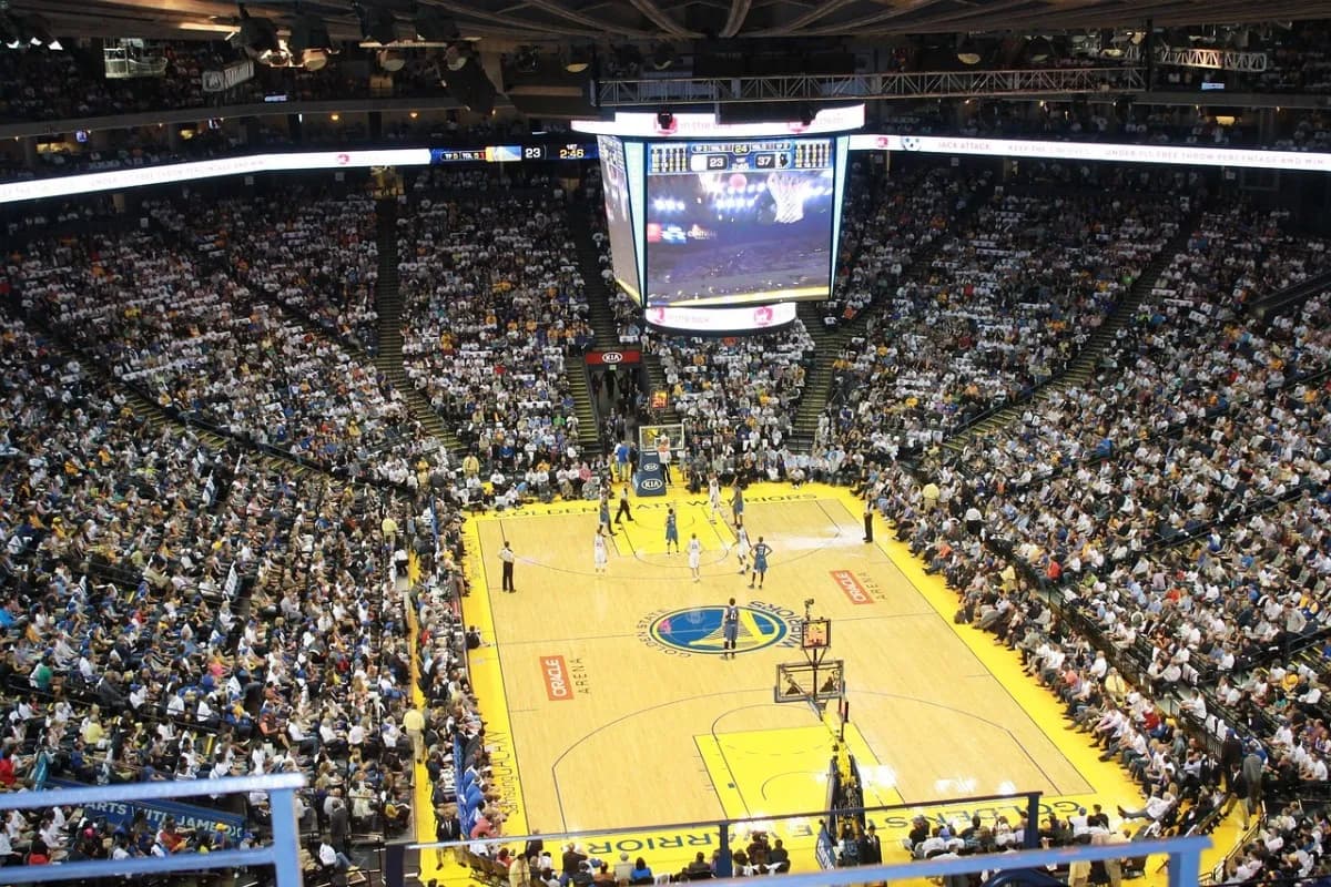 A packed indoor basketball arena seen from the upper deck