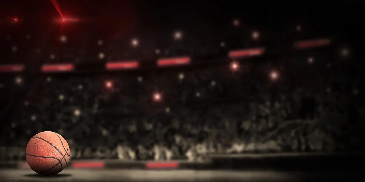 A basketball on a court in a darkened arena