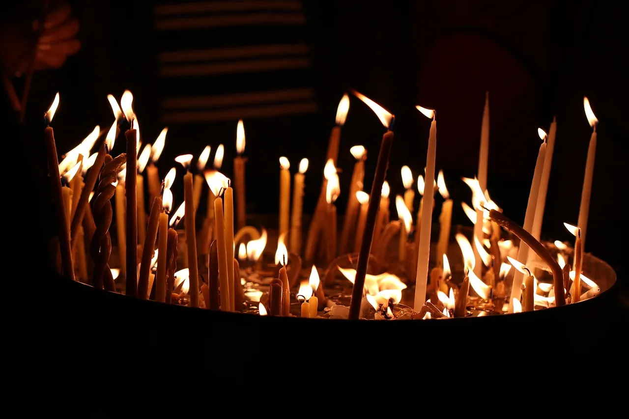 Rows of lit prayer candles glowing in the dark