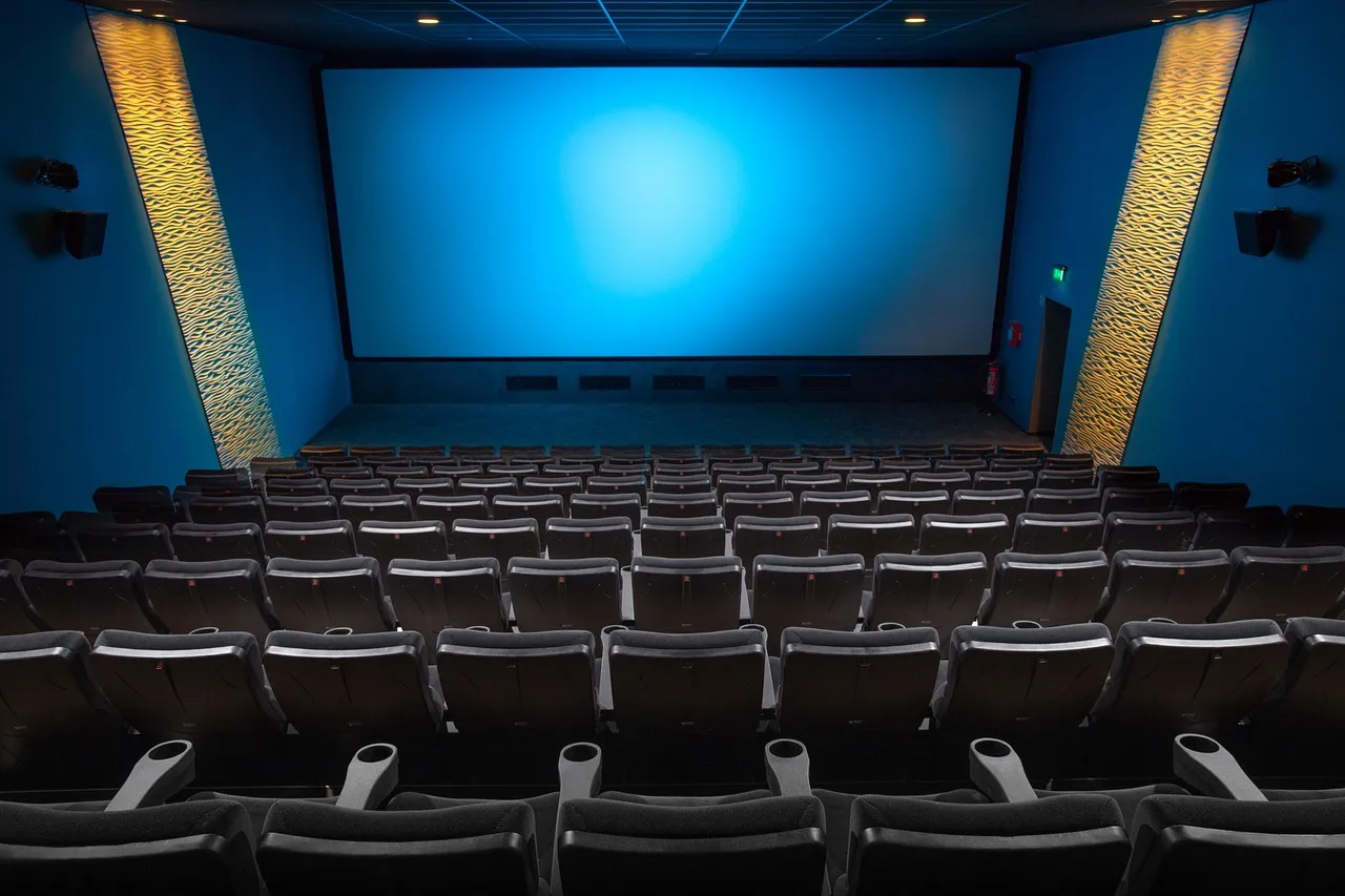 Empty cinema hall with rows of seats facing a large screen