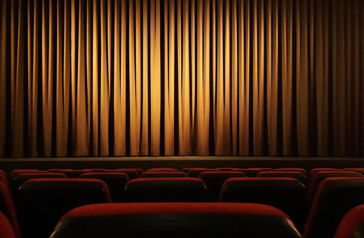 A cinema with red seats and a closed curtain