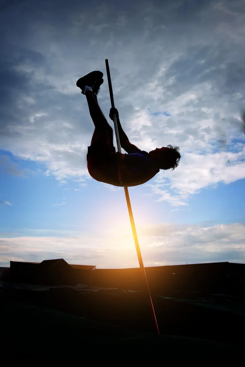 Silhouette of a pole vaulter in mid-jump against the sky